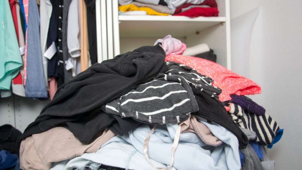 pile of messy clothes in front of a wardrobe