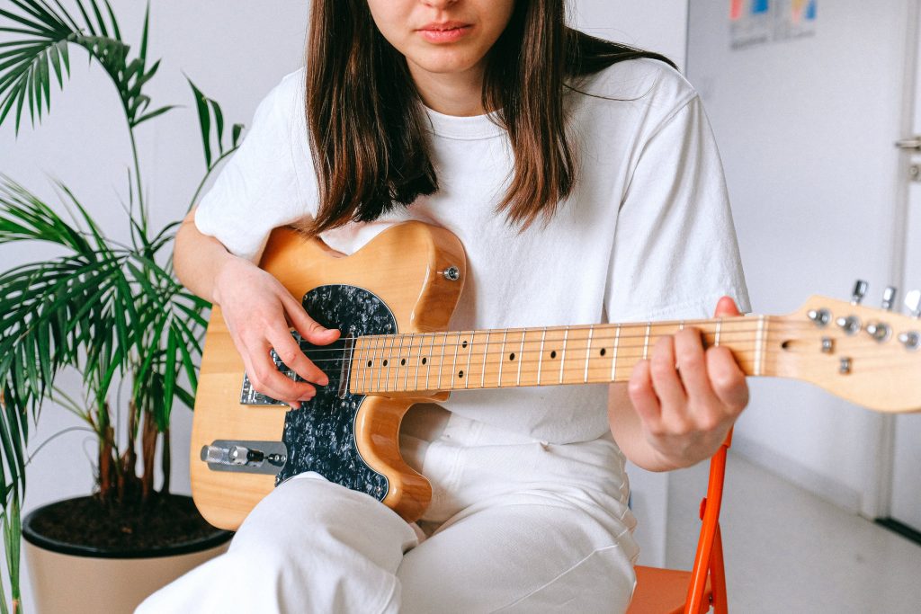 Woman in white shirt playing an electric guitar.