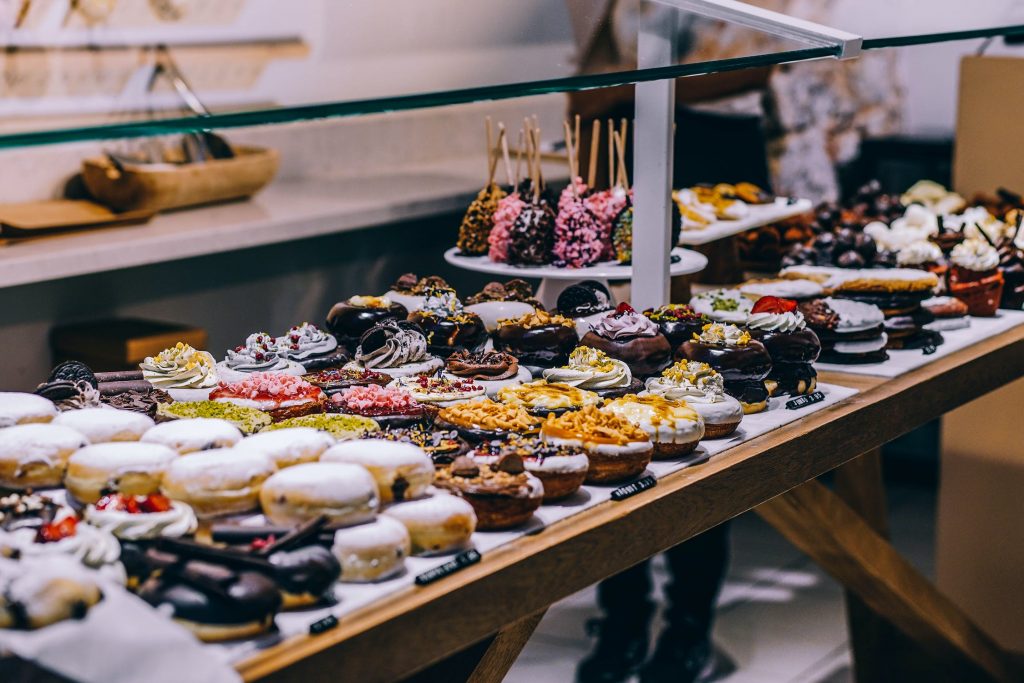 cakes and donuts on a stand at a food market.